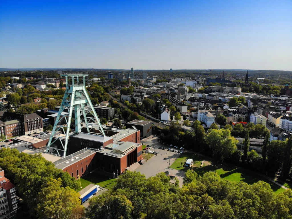 Luftaufnahme des bardusch Standorts in Bochum mit markantem Förderturm, umliegenden Gebäuden und Blick über die Stadtlandschaft des Ruhrgebiets.