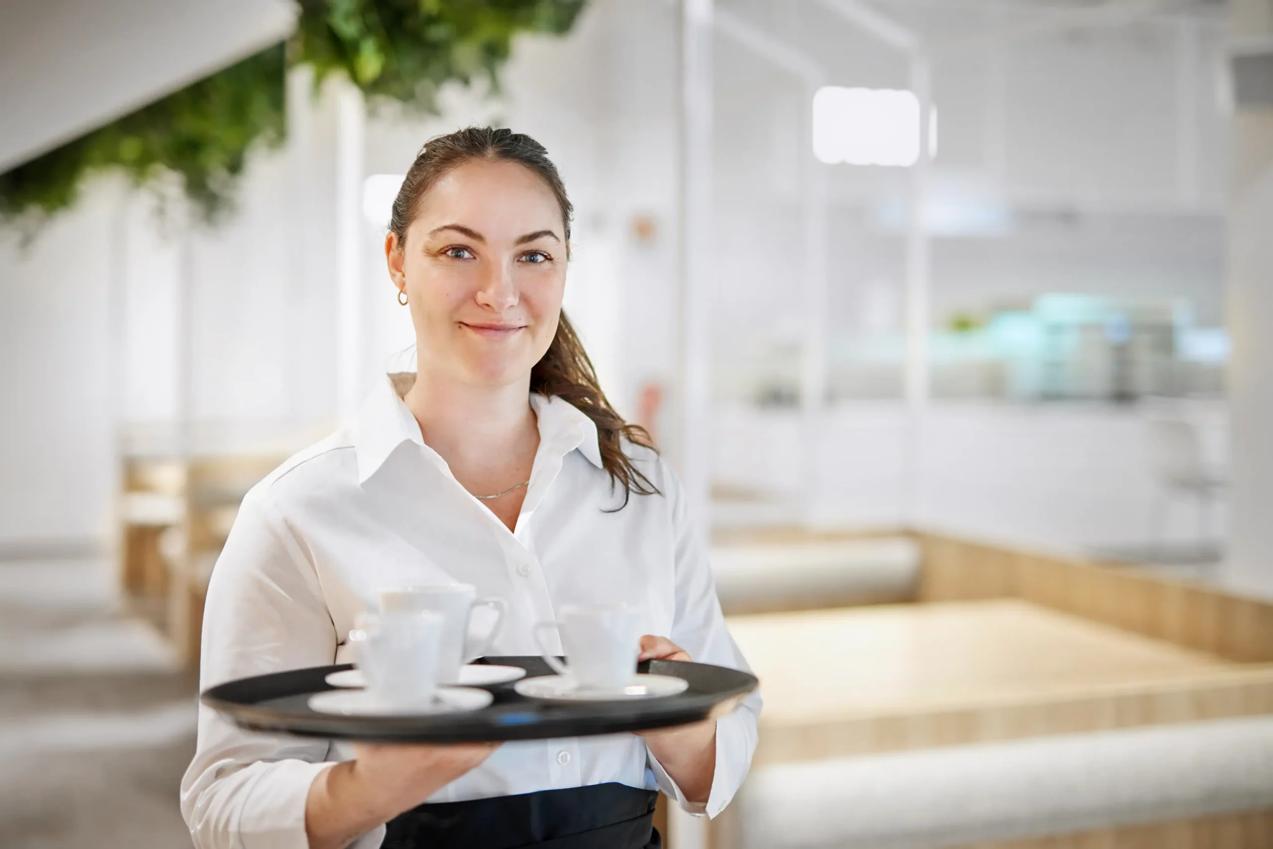 Servicekraft in der Gastronomie mit Tablett und Arbeitskleidung