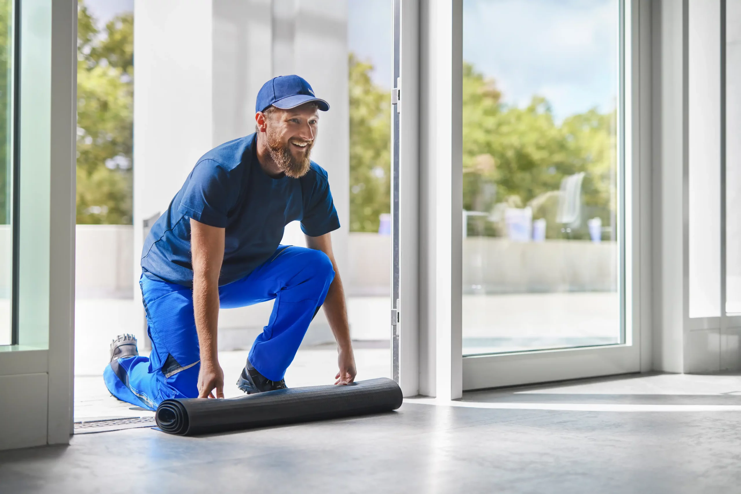Servicefahrer von bardusch rollt eine Schmutzfangmatte für den Mattenwechsel zusammen
