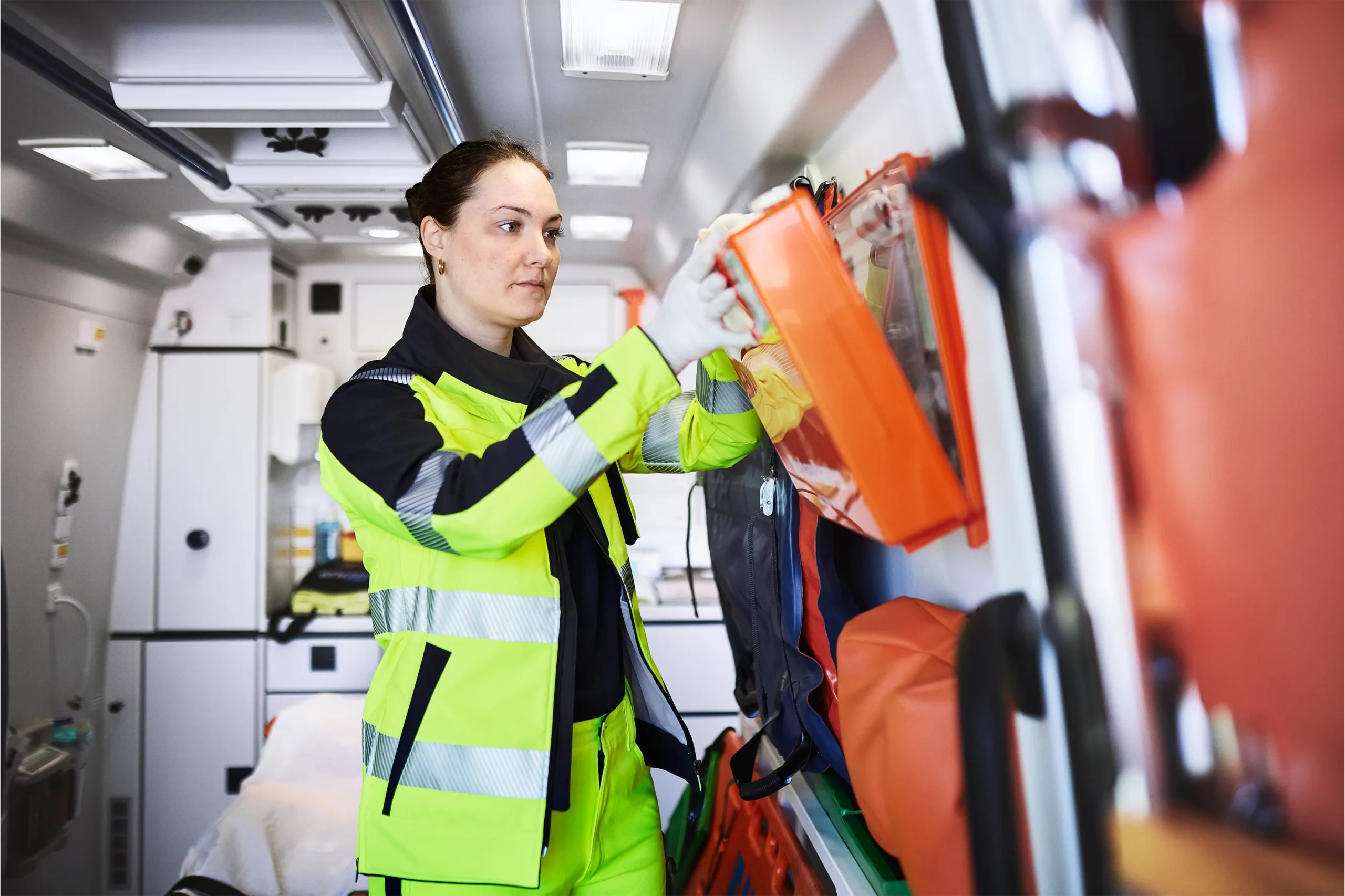 Rettungssanitäterin in gelber Arbeitsjacke im Einsatzwagen.
